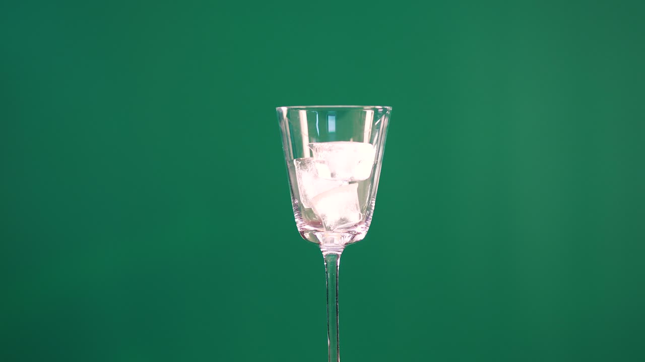 Un bicchiere con cubetti di ghiaccio su uno sfondo green screen, che mostra un movimento minimo e un'illuminazione costante