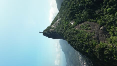 Vertical-drone-flight-approaching-famous-Christ-The-Redeemer-on-mountaintop-against-blue-sky-in-Brazil