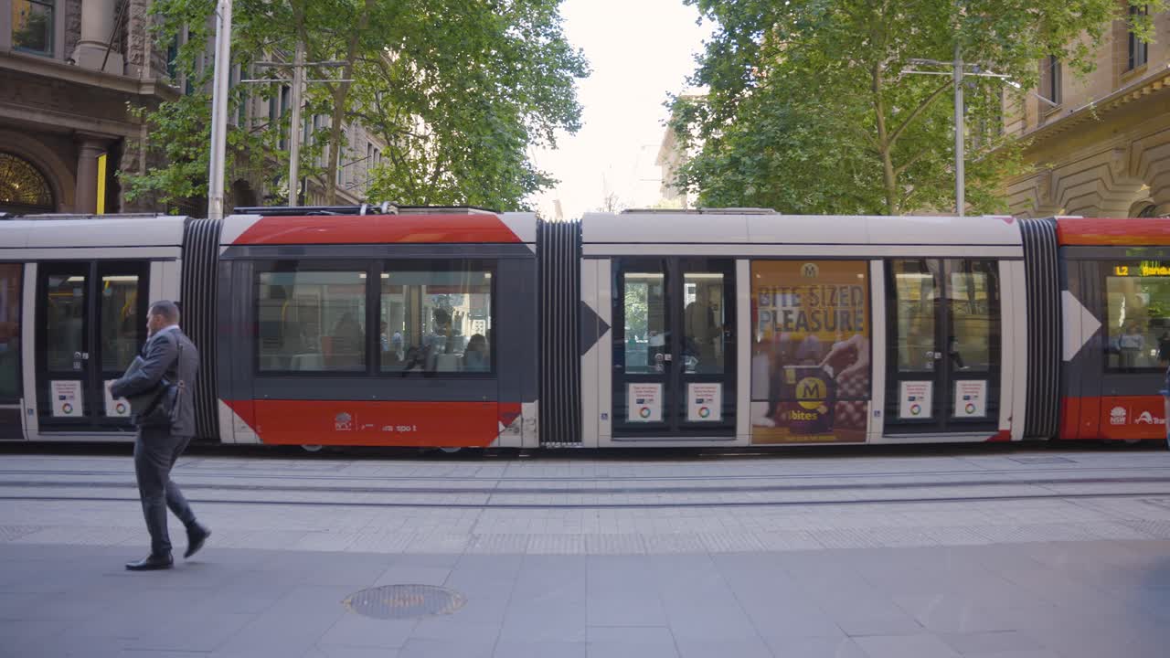 Commuters walking by, as the tram goes by in downtown Sydney, Australia during rush hour