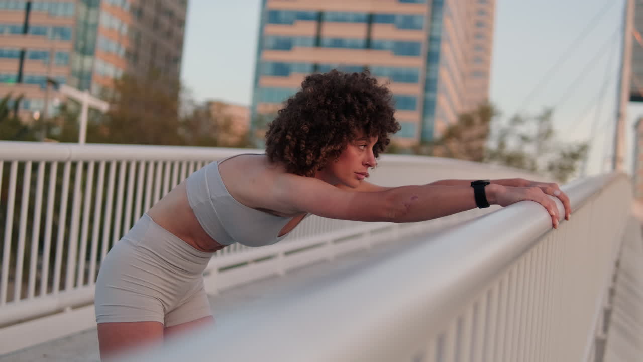 Woman Stretching on City Bridge