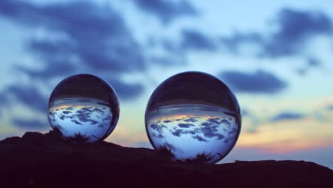 view of sunset in side two crystal balls on a timber.