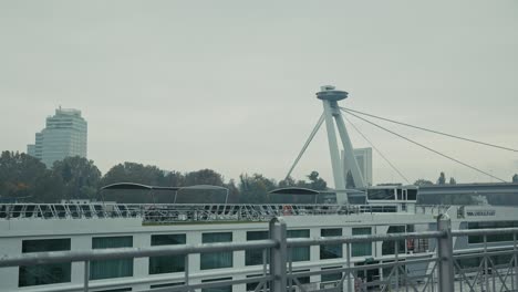 modern ufo bridge over the danube river in bratislava with a docked cruise ship