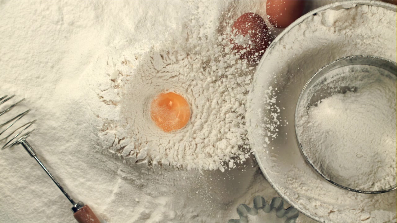 Kuning Telur Jatuh ke dalam Tepung di atas Meja dengan Bahan-bahan Kue