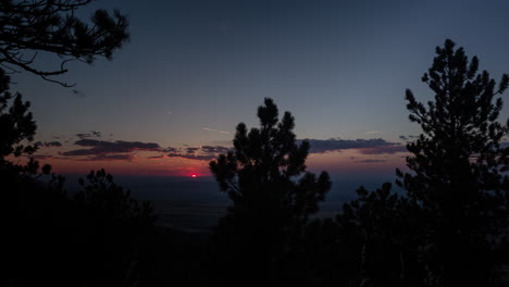 Lapso-De-Tiempo-De-Una-Puesta-De-Sol-Roja-Ardiente-Detrás-De-Los-árboles-En-Las-Altas-Llanuras-Del-Centro-De-Wyoming