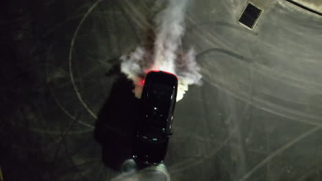 aerial view above a car drifting at a parking lot, during nighttime - top down, drone shot