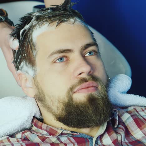 joven hipster que se lava el pelo en el salón