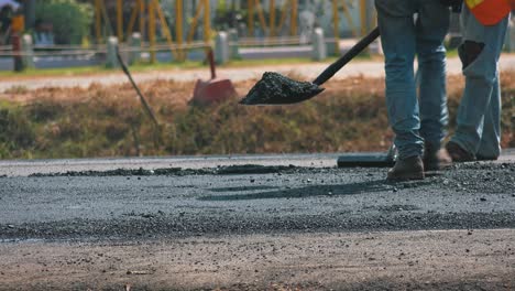 construction workers manually flattening a newly laid road surface ready for the steam roller