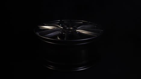 moderna hermosa rueda de aleación de automóviles en forma de rayos que es resaltado por rayos de luz y brillo, fondo negro, humo