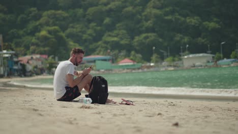 여행 가방을 들고 해변에 앉아 필리핀 엘니도의 유명한 열대 섬을 즐기는 관광객 - 여름 휴가에 완벽함 - 와이드 샷