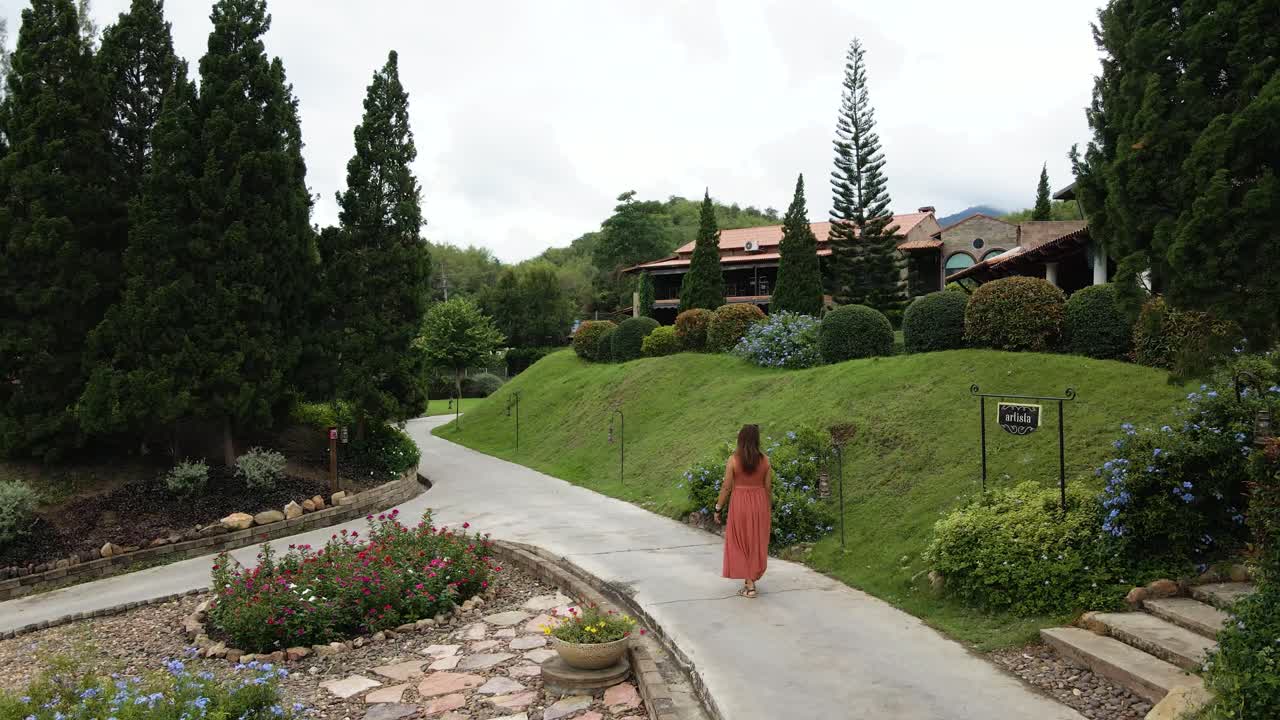 dama de rojo caminando a lo largo de un jardín botánico italiano en ratchaburi, tailandia