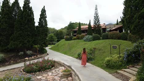 lady in red walking along a botanical italian garden resort in ratchaburi, thailand