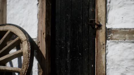 old wood wheel and black door at white house