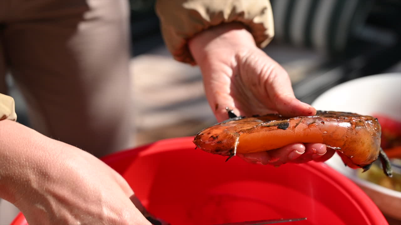 Woman cleaning red grilled peppers for salad