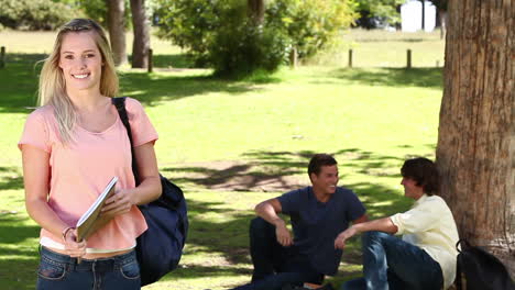 woman waving towards her friends who are sitting behind her before she looks at the camera