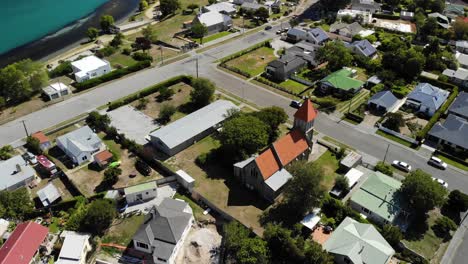 vista aérea de la iglesia católica y el paisaje urbano de cromwell, nueva zelanda, por el río clutha en un día soleado, revelando una toma de dron