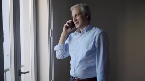 positive mid adult man chatting on phone