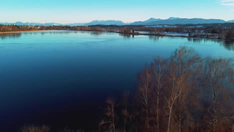 4k uhd 空中無人機飛行在巴伐利亞冰凍湖和樹頂上向後移動 靠近阿爾卑斯山在冬季在德國靠近奧地利