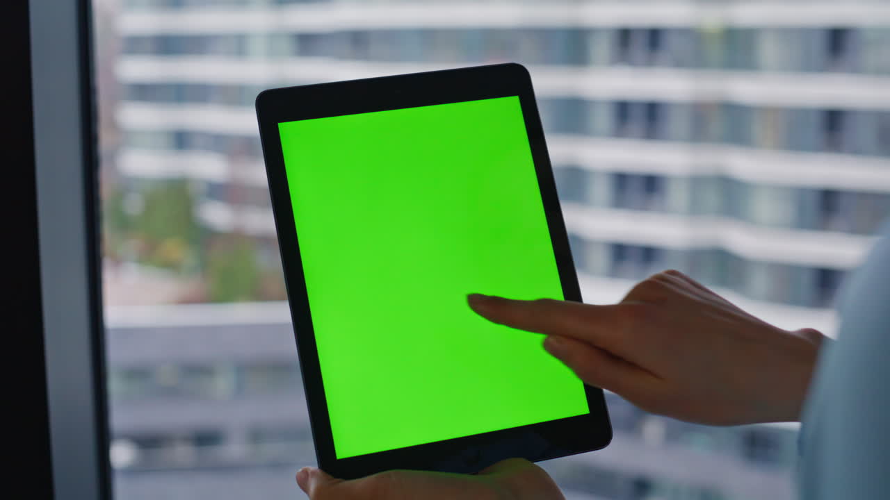 Tablet with green screen in front of office building
