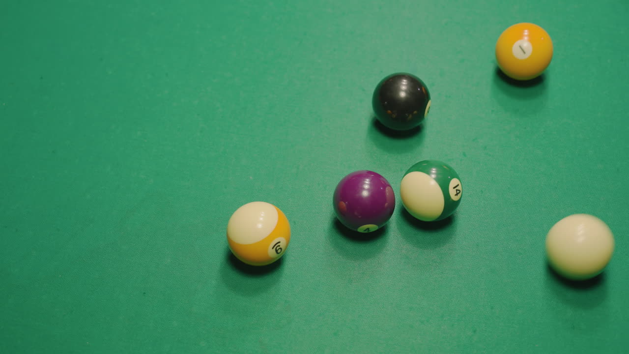 Vibrant billiard balls scattered across green pool table after powerful break shot, rolling dynamically in various directions under bright overhead light, creating energetic motion