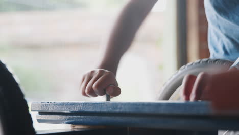 Close-up-of-pre-teen-boy's-hands-screwing-in-a-bolt-while-making-a-racing-kart-with-his-dad,-selective-focus