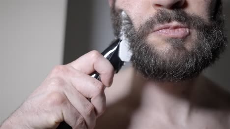 man uses electric trimmer on beard in slow motion