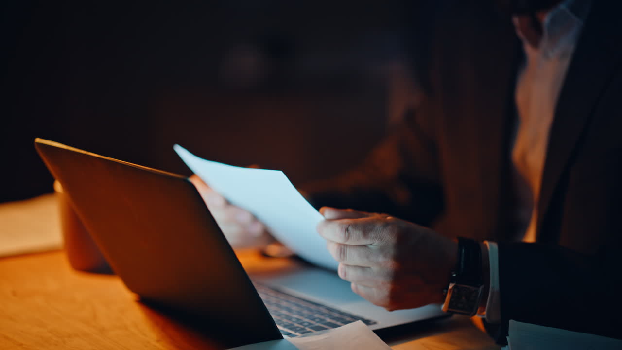 Satisfied man working late taking papers at night panoramic apartment closeup