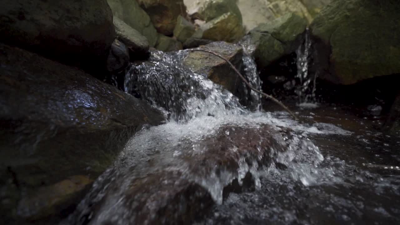 Carrellata al rallentatore di un piccolo ruscello che scorre sulle rocce