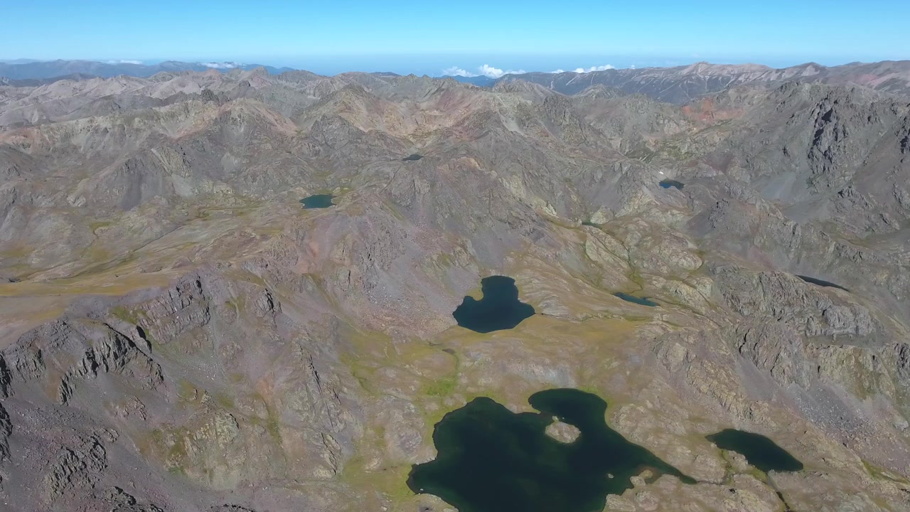 Vista aerea di aspra catena montuosa e laghi alpini.