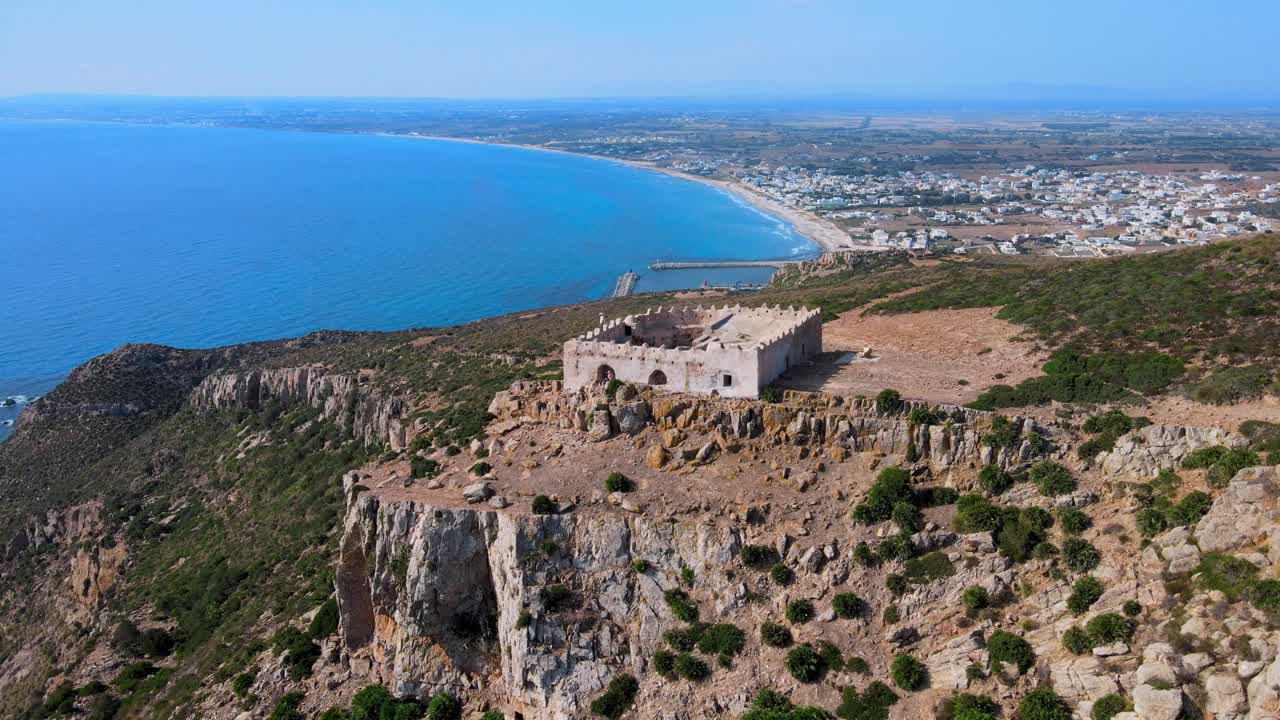 A historic fortress perched on rugged cliffs overlooks the serene Mediterranean Sea, blending ancient architecture with natural beauty in a picturesque coastal setting.