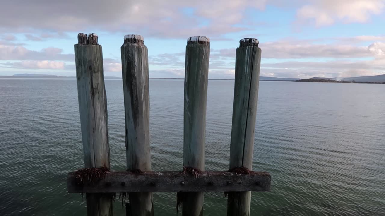 A tranquil view of seaport piles or fenders at an old derelict wharf with sea in back ground