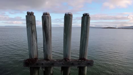 a tranquil view of seaport piles or fenders at an old derelict wharf with sea in back ground