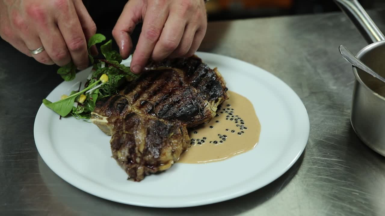 셰프가 맛있는 리브 아이 스테이크를 준비하고 있습니다.