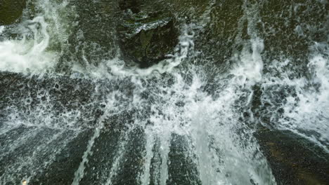 waterfall from a dam goes into the river in slow motion and the water in splashing when it hits the stone and the concrete