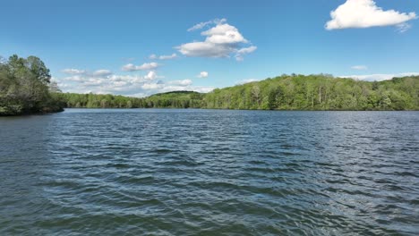 low altitude flight over tranquil mill creek lake during sunny day with blue sky in america. forest landscape and puffy clouds at sky. dolly forward shot.
