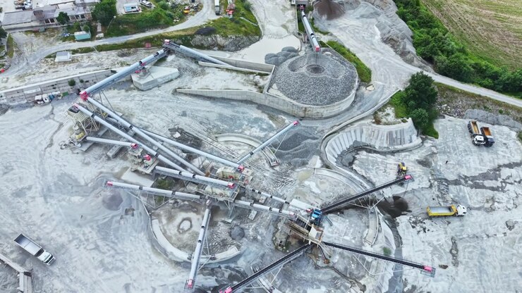 Highangle shot of bustling gravel extraction site with machinery. Comprehensive aerial perspective showcasing ongoing mineral extraction processes and infrastructure