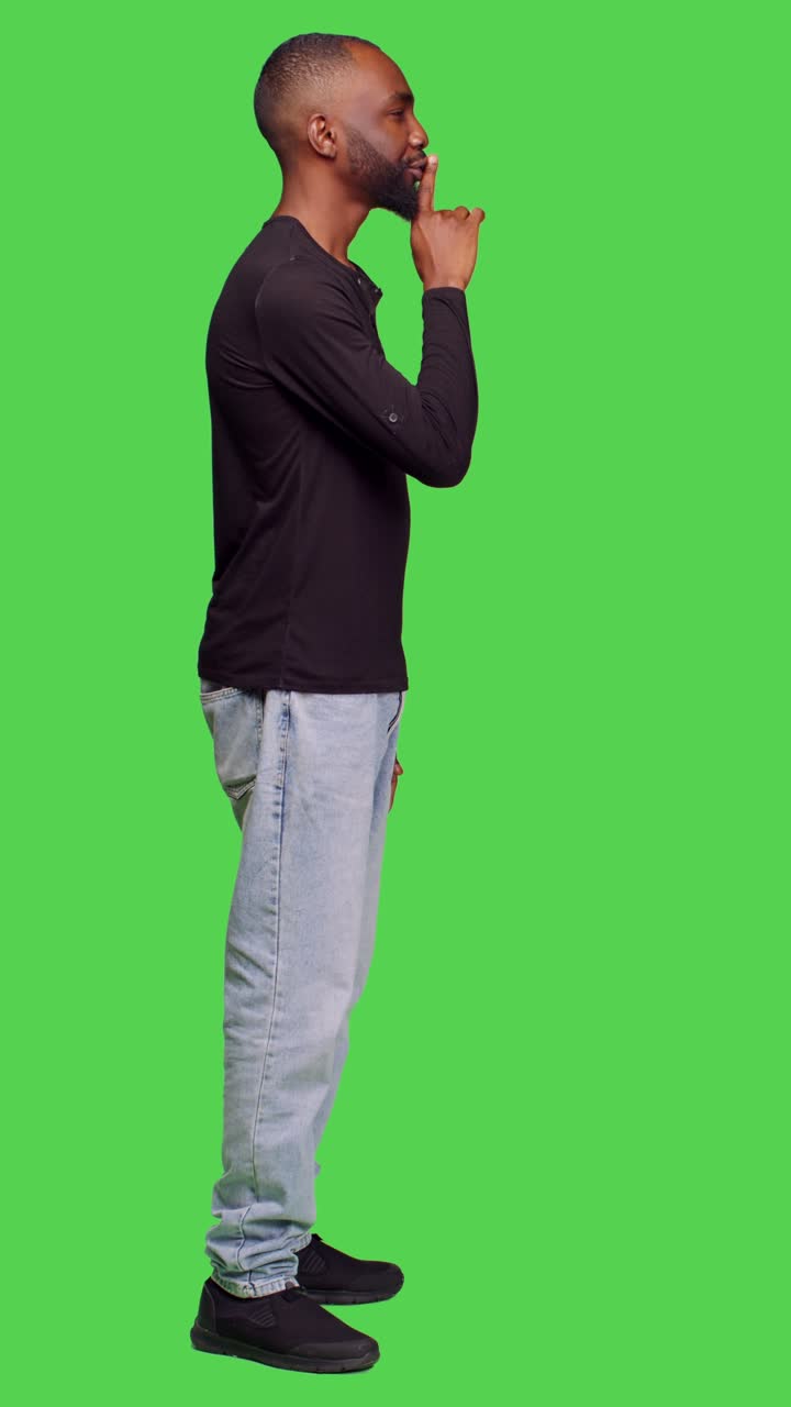 Vertical video: Profile of young adult showing hush sign on camera