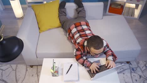 hombre enano trabajando en la computadora acostado en casa.