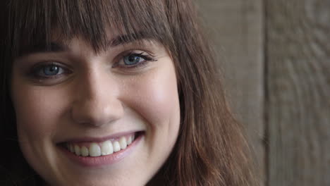 Retrato-De-Una-Hermosa-Joven-Sonriendo-Mirando-A-La-Cámara-Ojos-Azules-Belleza-Femenina-Caucásica-Sobre-Fondo-De-Madera