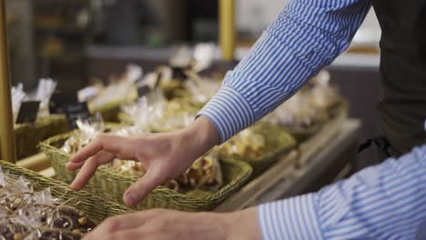 Close-up-male-hands-putting-cookies-on-the-counter-in-bakery-store