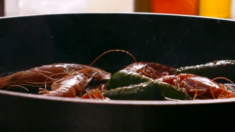 chef adding salt to frying shrimps