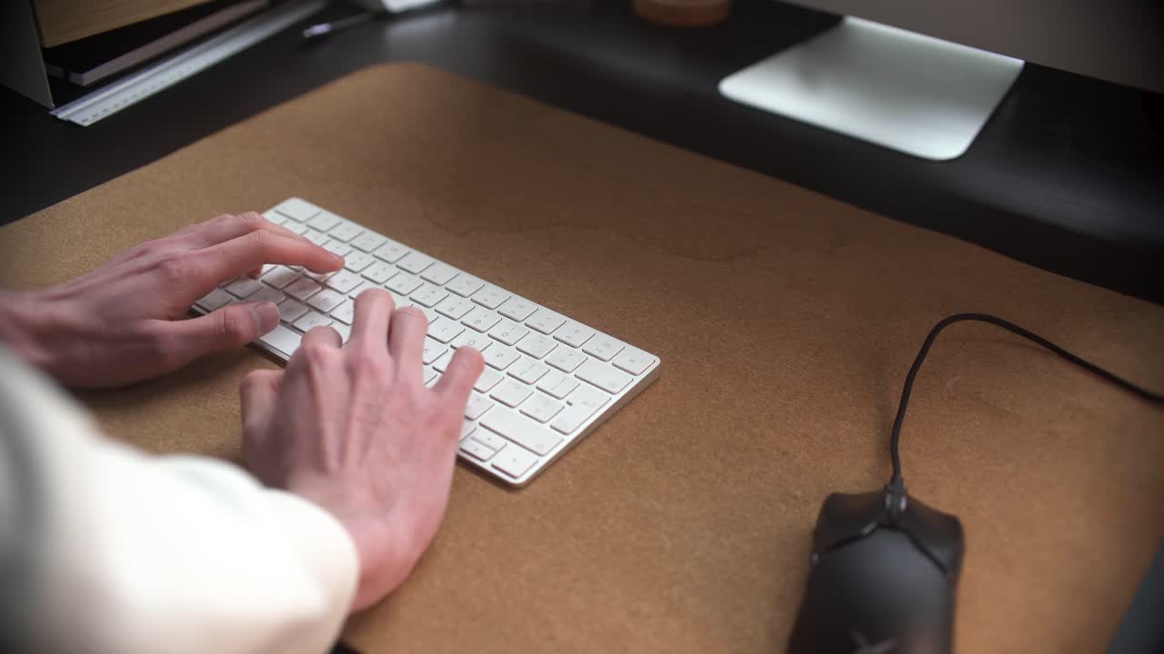 Man behind standing desk, typing on his keyboard, working in his office