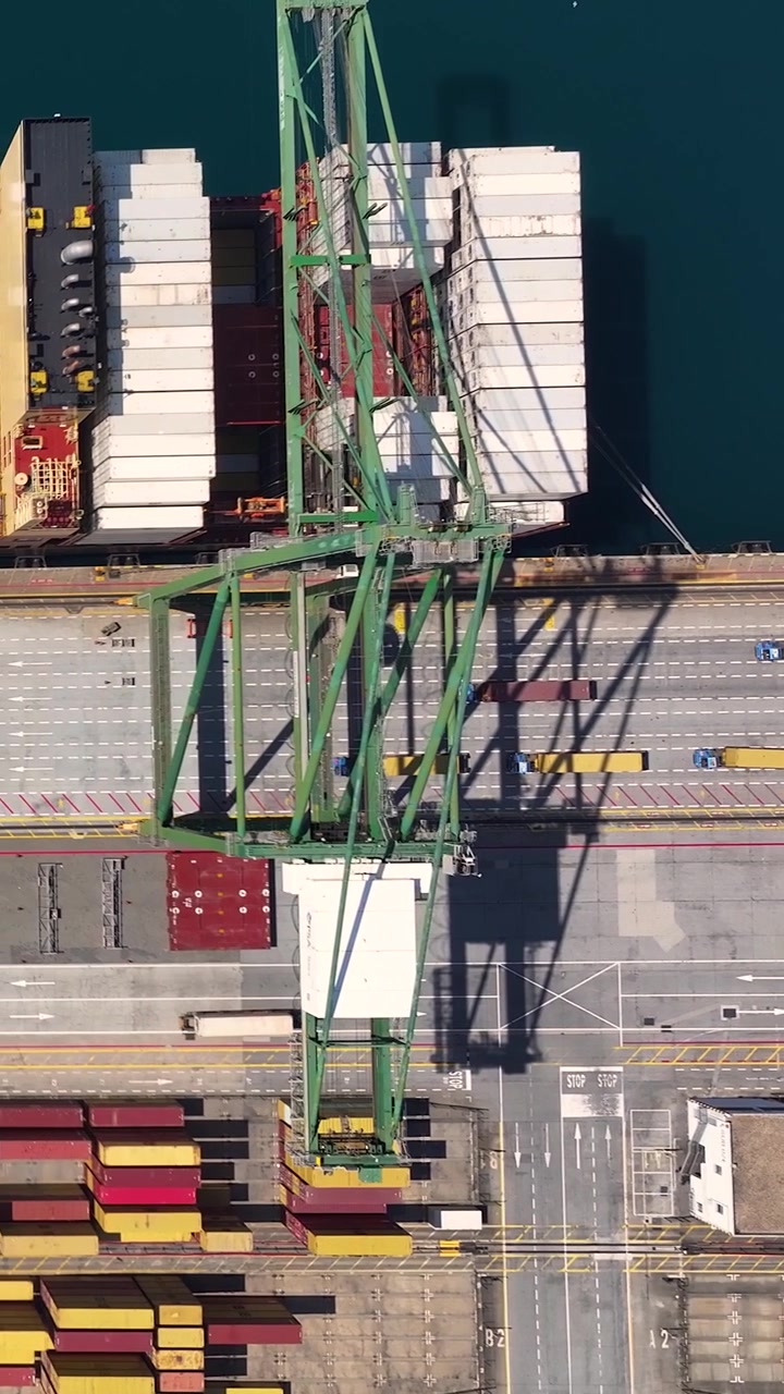 Container terminal shows several shipping containers stacked and organized. Cranes move containers to and from ships at the port. This is a key hub for international freight transport.