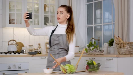 mujer haciendo una ensalada y haciendo un video de cocina selfie