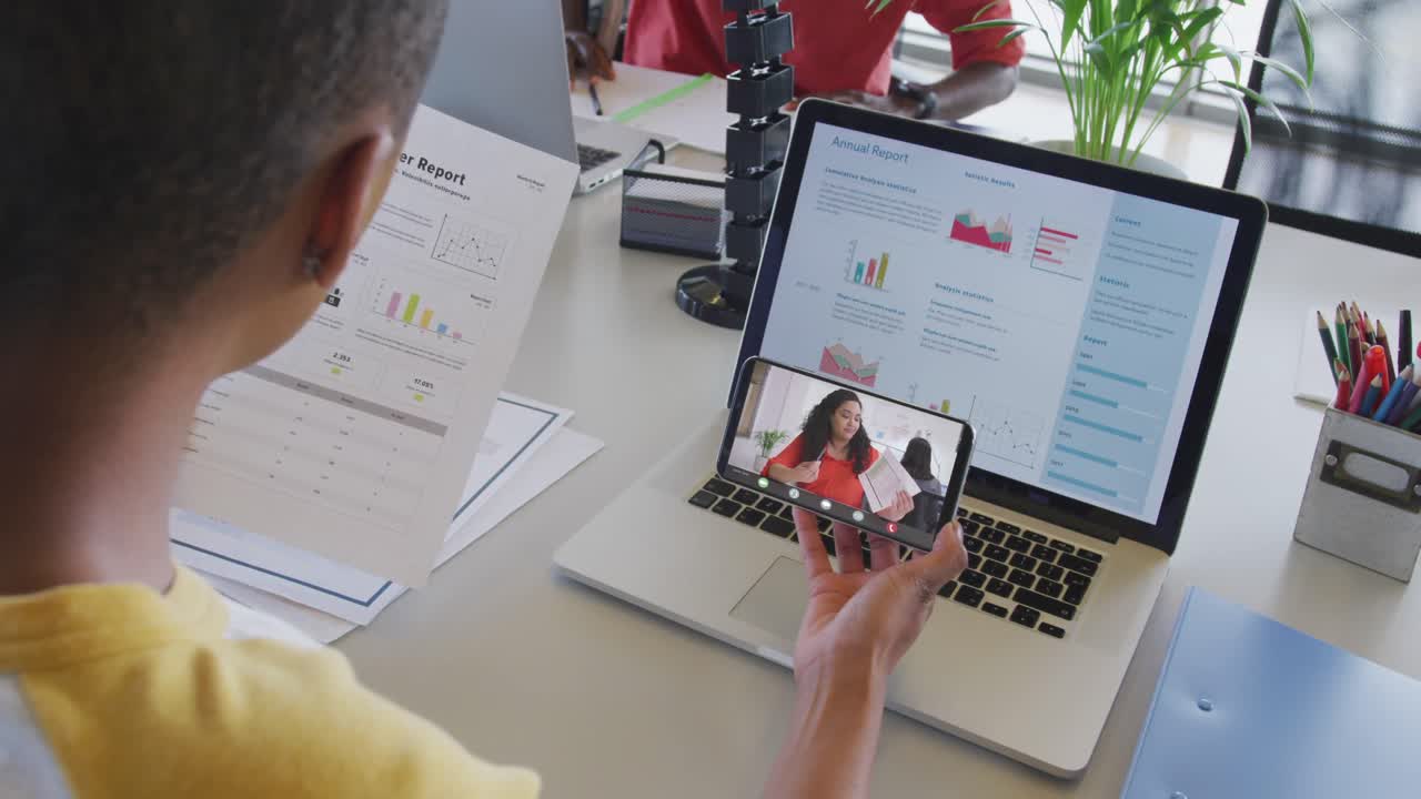 mujer de negocios afroamericana que usa un teléfono inteligente para una videollamada con un colega de negocios biracial