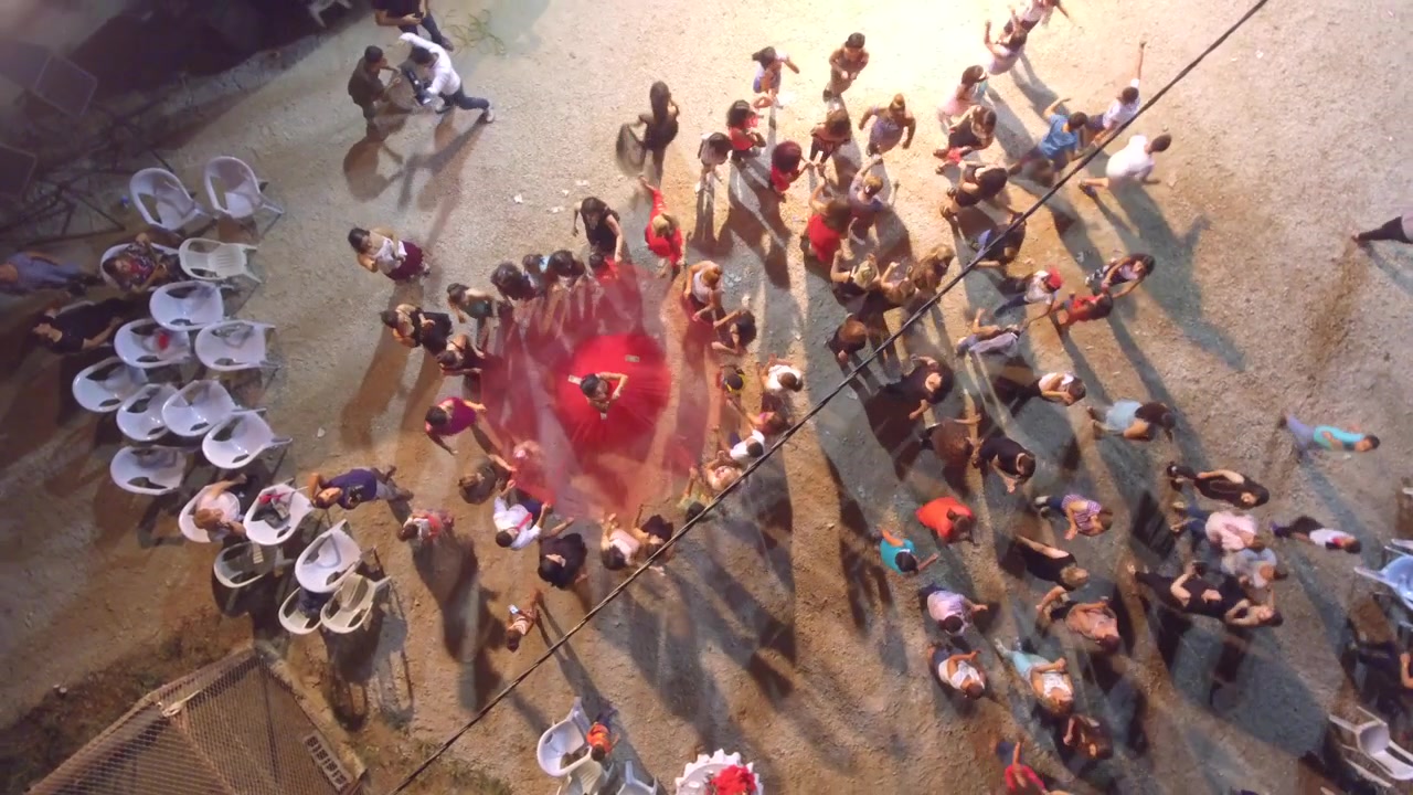 Luftfoto af mennesker, der danser i en cirkel om natten