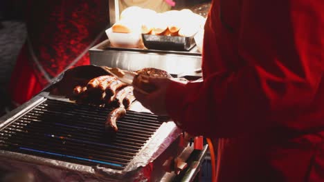 Primer-Plano-De-Un-Hombre-Asando-Salchichas-Asadas-Afuera-En-La-Parrilla-Durante-El-Evento-De-La-Fiesta