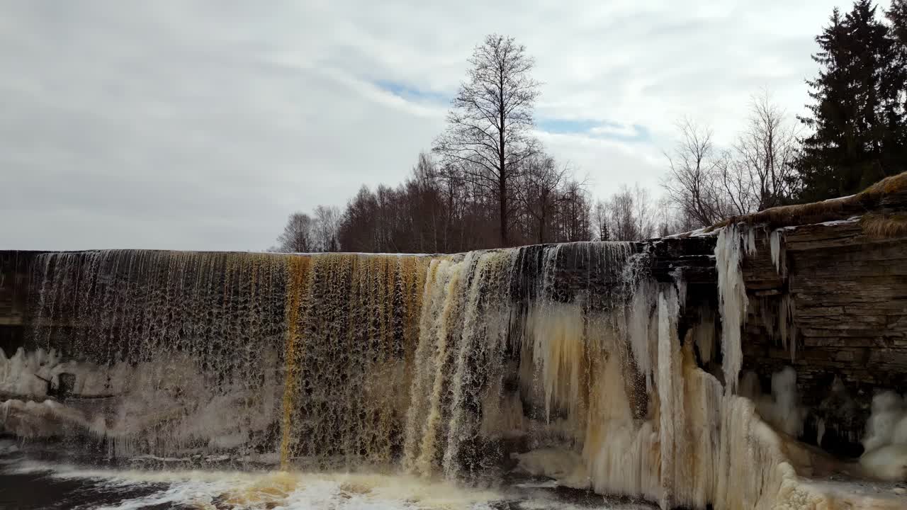 catarata de jegala parcialmente congelada en un día nublado de invierno, dolly aéreo fuera