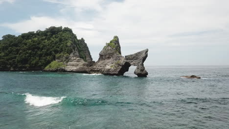 jagged, eroded rock of batupadasan island stands in shallow bali bay