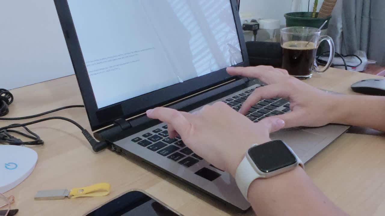 Hands typing on a laptop, showcasing a connected modern lifestyle with smartwatch and coffee.