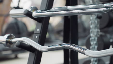 stacked sleek chrome cable machine handles and attachments on sturdy rack in bright modern gym with blurred cardio machines and weight plates in background showcasing professional fitness environment